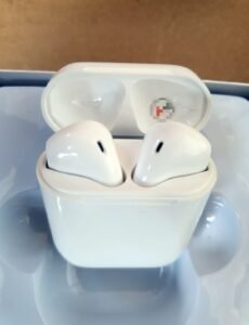 White wireless earbuds in their open charging case resting on a light blue surface, viewed from above.Apple AirPods in case ready to use.