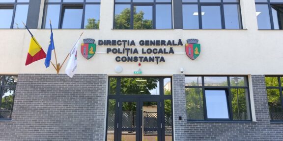 Facade of the Constanța Local Police Directorate building with Romanian and EU flags, crest shields, and glass entrance doors.