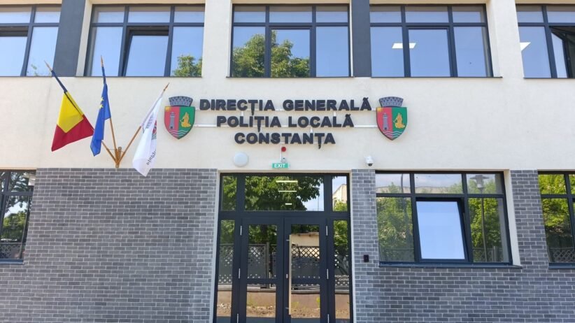Facade of the Constanța Local Police Directorate building with Romanian and EU flags, crest shields, and glass entrance doors.