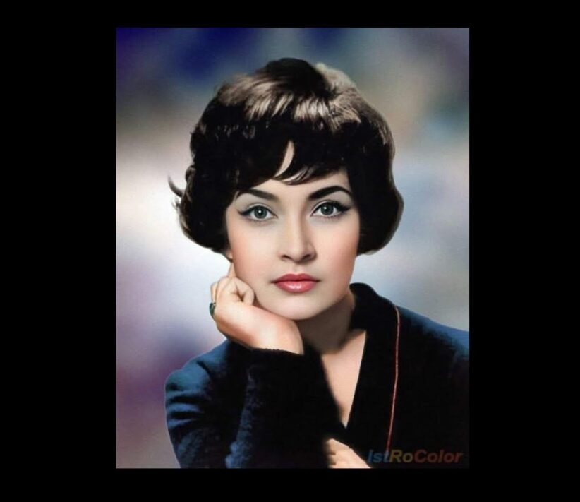 Vintage studio portrait of a woman with short dark hair, resting her chin on her hand in a blue blazer.