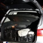 Open hatchback trunk at night, filled with black trash bags and a white cardboard box.