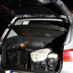 Open hatchback trunk at night, filled with black trash bags and a white cardboard box.