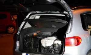 Open hatchback trunk at night, filled with black trash bags and a white cardboard box.