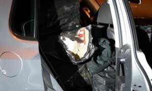 Open car door showing a large black plastic bundle inside the rear seat area of the car at night.