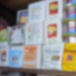 Blurred display shelf holding multiple white brochures and colorful packaging on the right side.