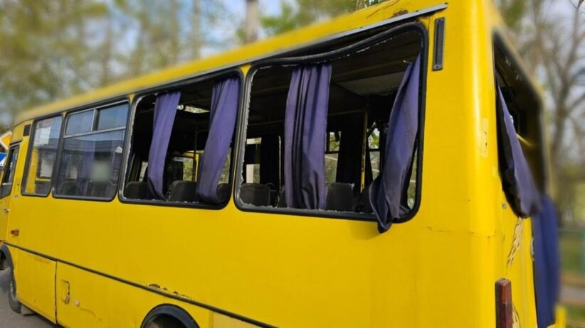Yellow school bus with open windows and purple curtains, parked outdoors