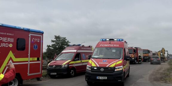Convoy of red emergency vehicles, including SMURD ambulances, parked on a road under a cloudy sky