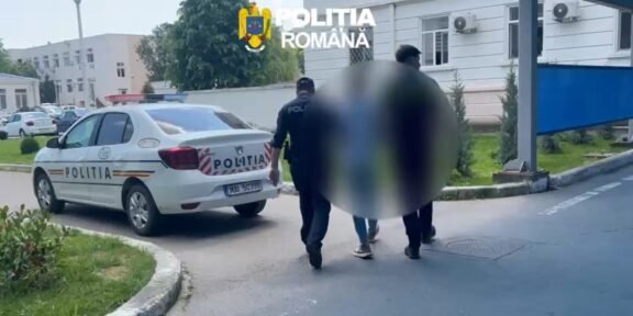 Romanian police car parked outside a building as officers escort two blurred individuals into the entrance.